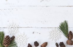 pine needles, acorns, and handmade snowflakes on a white wooden background